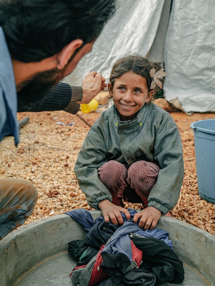 Young girl in a Syrian refugee camp receives encouragement, displaying resilience and hope.